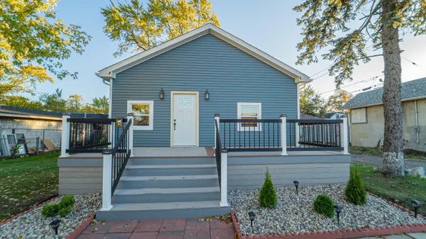 a view of a house with wooden fence next to a yard
