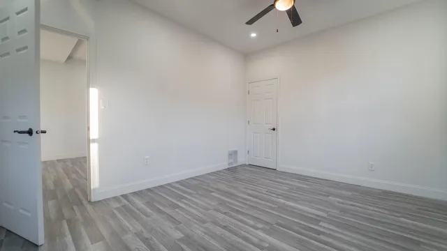 an empty room with a ceiling fan and wooden floor