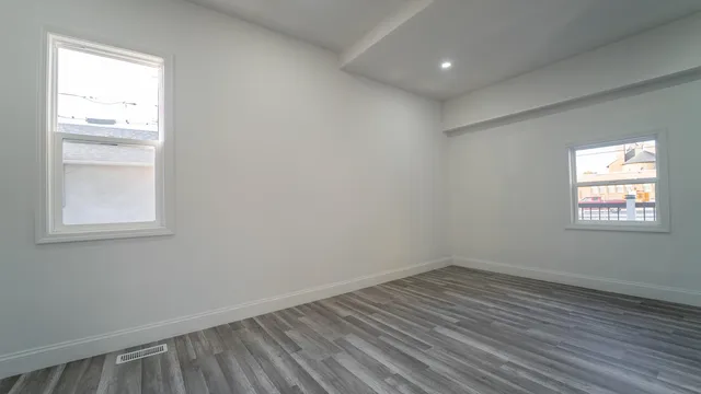an empty room with wooden floor and windows