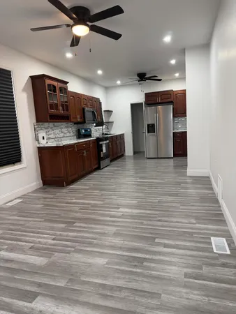 a large room with stainless steel appliances kitchen island stainless steel appliances wooden floor and chandelier