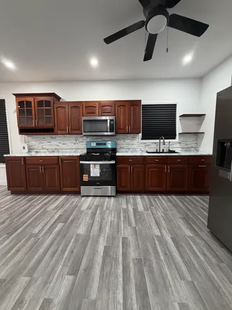 a large kitchen with stainless steel appliances wooden floor and a counter top space