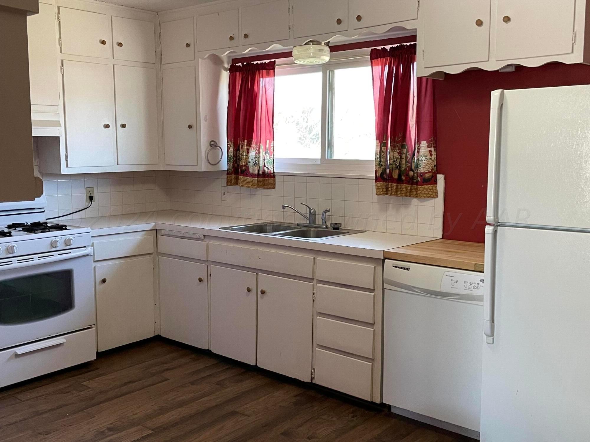 2014 South Drake Street Perryton, TX 79070 - Photo 4 of 10 a kitchen with a refrigerator sink and cabinets