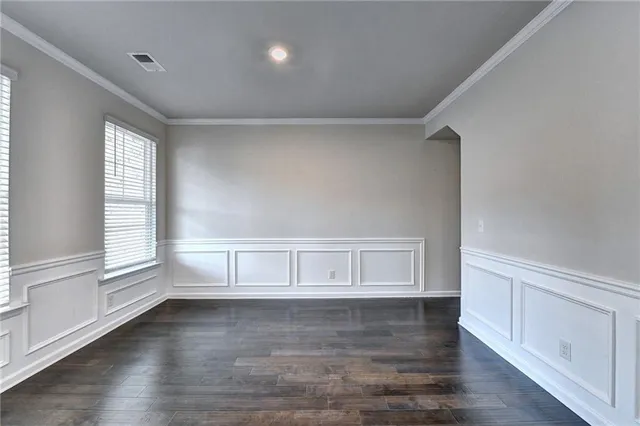 a view of an empty room with wooden floor and cabinets
