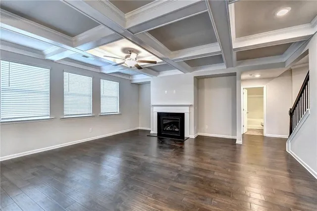 an empty room with wooden floor fireplace and windows