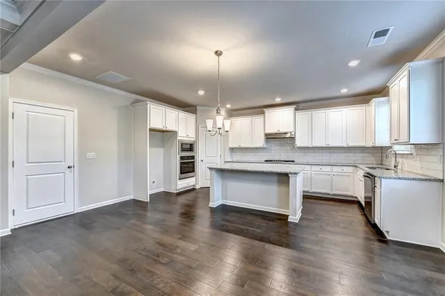a large kitchen with cabinets wooden floor and stainless steel appliances