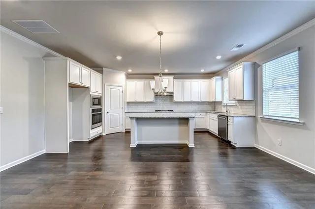 a kitchen with stainless steel appliances kitchen island granite countertop a stove a sink a refrigerator and white cabinets with wooden floor