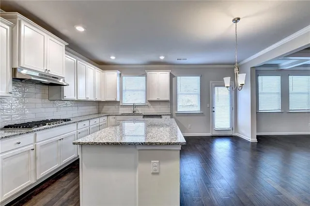 a large kitchen with granite countertop a large counter top space a sink stainless steel appliances and cabinets
