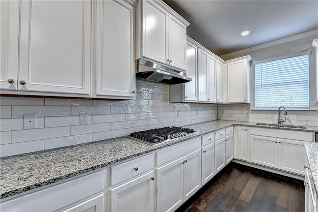 a kitchen with granite countertop white cabinets and a sink