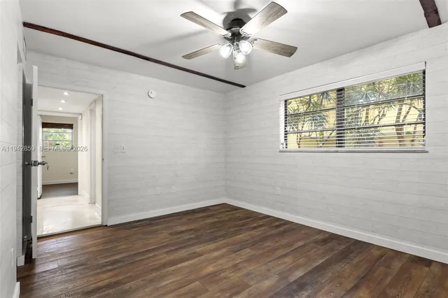 a view of an empty room with a window and wooden floor