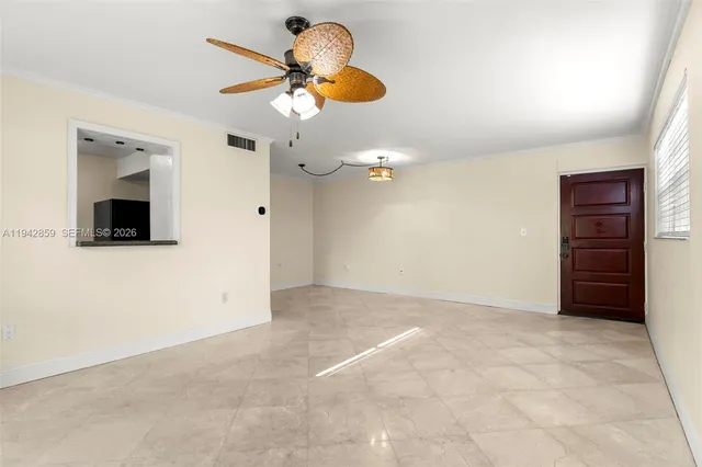 an empty room with a flat screen tv and chandelier fan