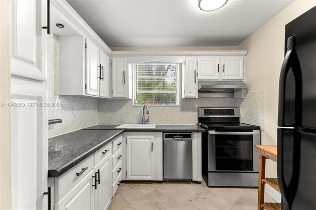 a kitchen with cabinets appliances and a window