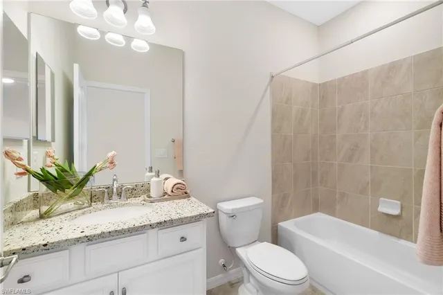 a bathroom with a granite countertop sink a toilet a mirror a bathtub and shower