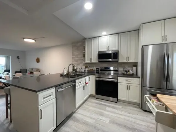 a kitchen with stainless steel appliances kitchen island granite countertop a table chairs sink and cabinets