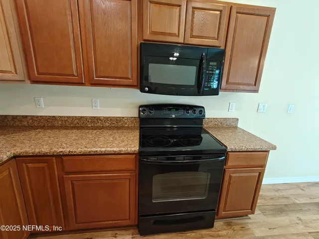 a kitchen with granite countertop wood cabinets and a stove top oven