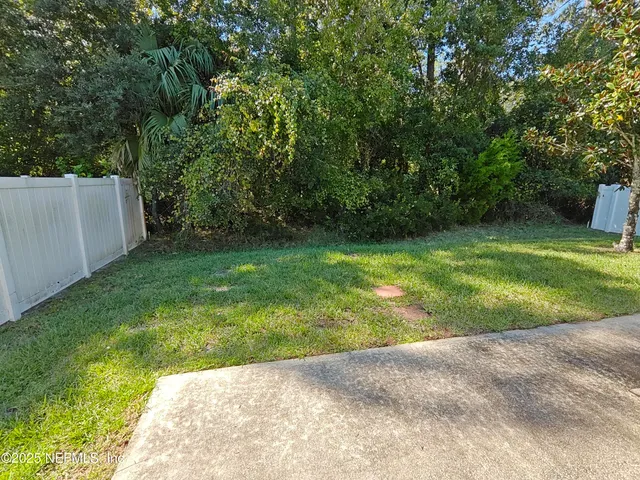 a backyard of a house with plants and large trees