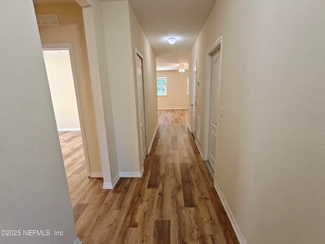 a view of a hallway with wooden floor and a bathroom