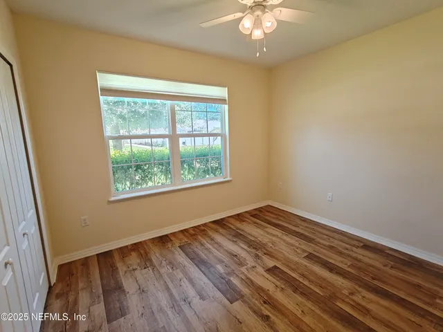 a view of an empty room with wooden floor and a window