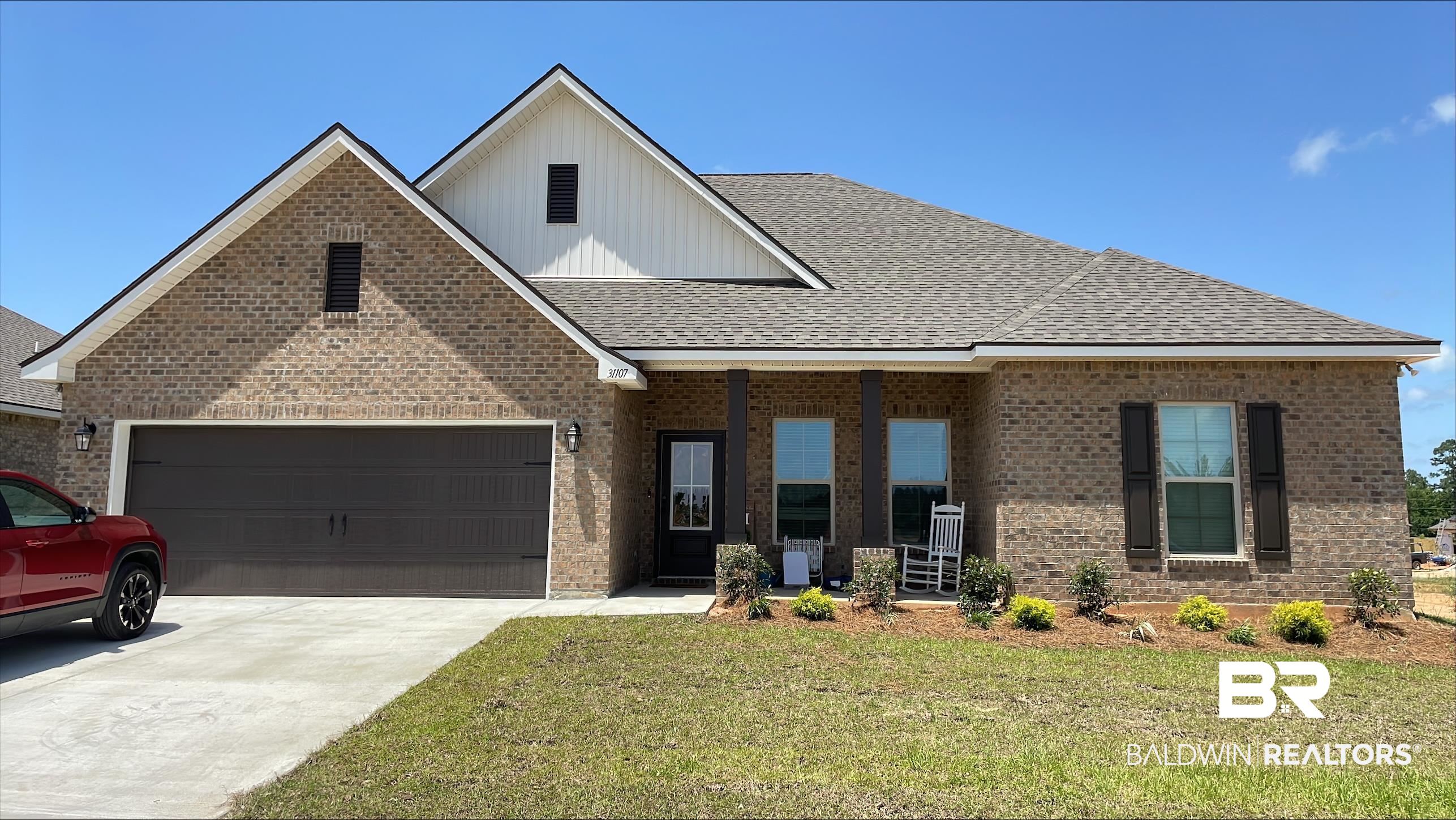 31107 Bauer Avenue Daphne, AL 36527 - Photo 1 of 3 View of front of home featuring a front yard, brick siding, a garage, a shingled roof, and driveway