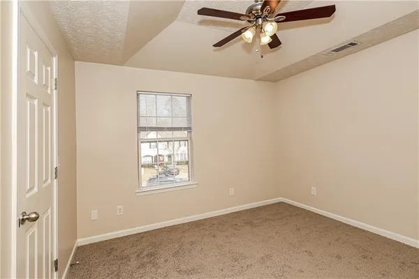 an empty room with windows and fan