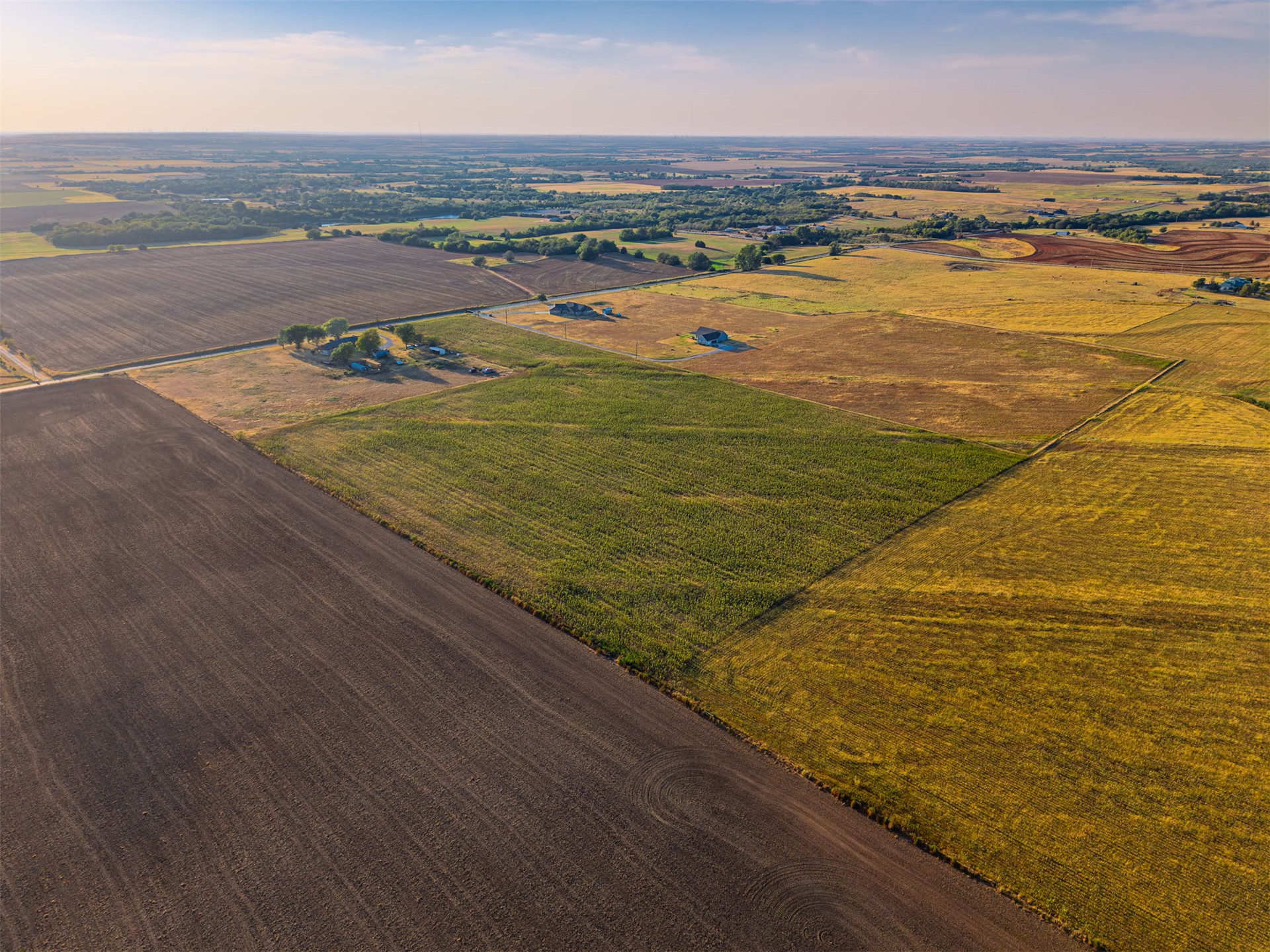 16 North Gregory Road Yukon, OK 73099 - Photo 24 of 34 Expansive land featuring diverse agricultural fields, including tilled earth, green crops, and golden crops
