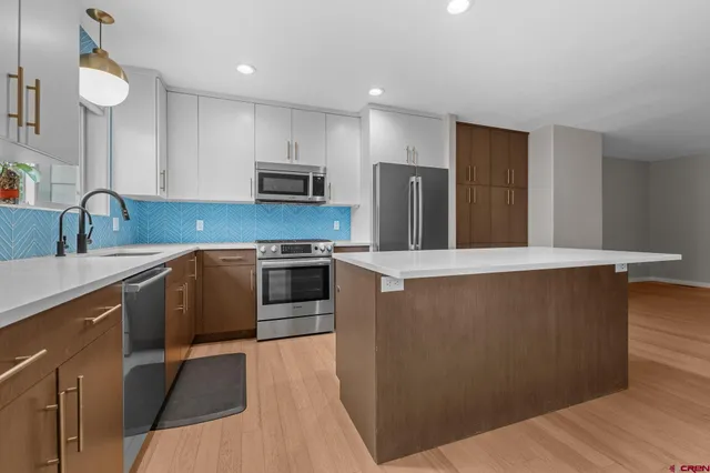 a kitchen with stainless steel appliances a stove a sink a microwave a refrigerator and cabinets