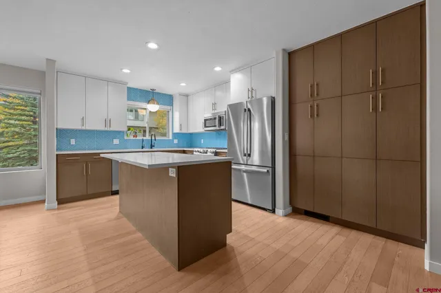 a kitchen with stainless steel appliances granite countertop a refrigerator a sink dishwasher and a stove with wooden floor