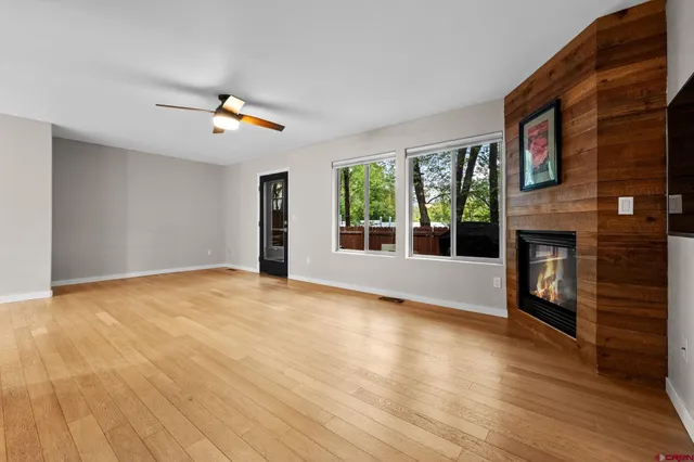 a view of empty room with wooden floor and fan