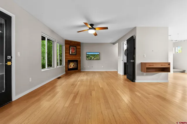 a view of a livingroom with wooden floor a ceiling fan and a window