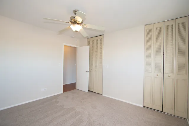 a view of an empty room with chandelier fan