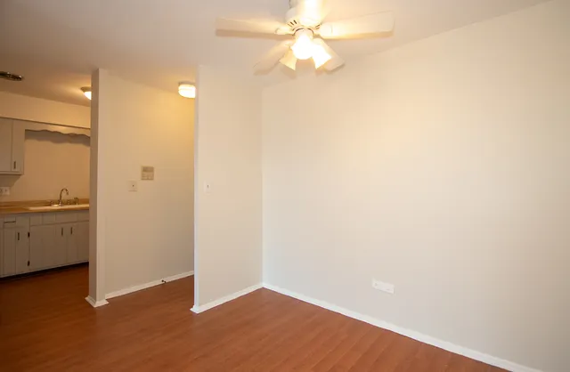 a view of a kitchen with wooden floor and a ceiling fan