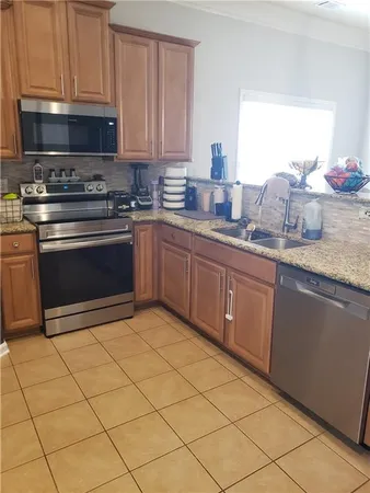 a kitchen with granite countertop a sink cabinets and stainless steel appliances