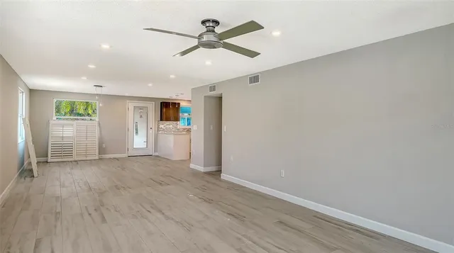 an empty room with wooden floor and windows