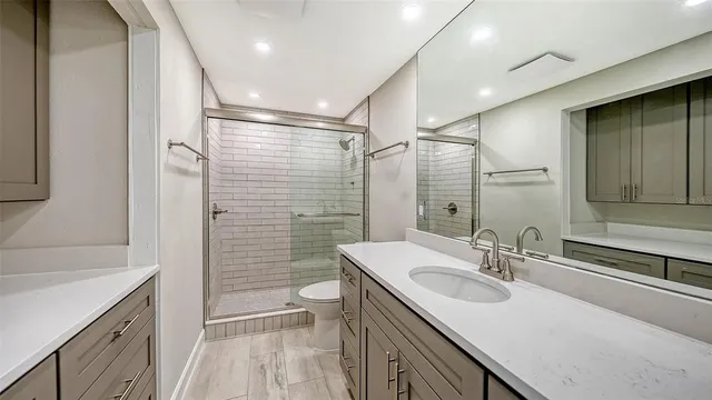 a bathroom with a sink a toilet a mirror and shower