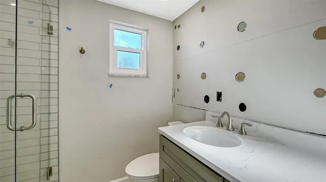 a bathroom with a granite countertop sink toilet and mirror