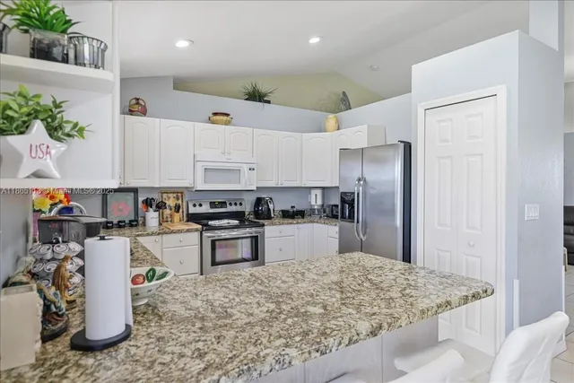 a kitchen with stainless steel appliances kitchen island granite countertop a refrigerator and a sink