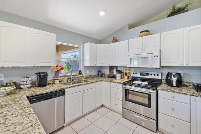 a kitchen with granite countertop white cabinets sink and white appliances