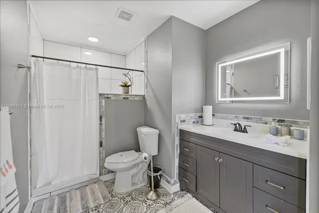 a bathroom with a toilet a sink a mirror a toilet and vanity