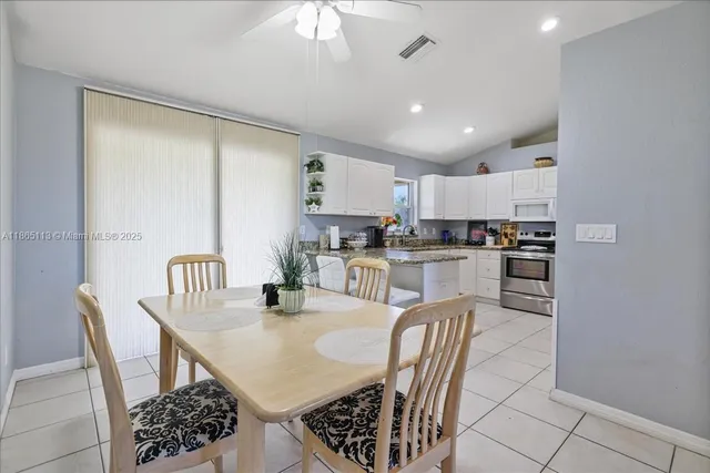 a kitchen with a dining table chairs and refrigerator
