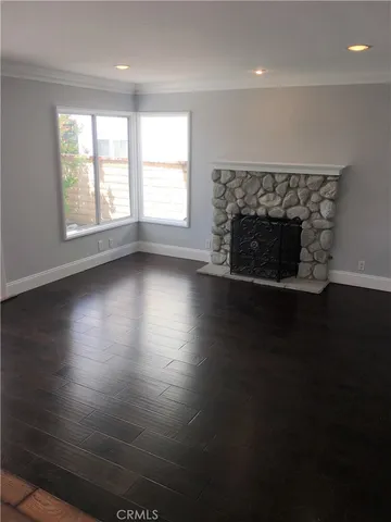an empty room with wooden floor a fireplace and windows