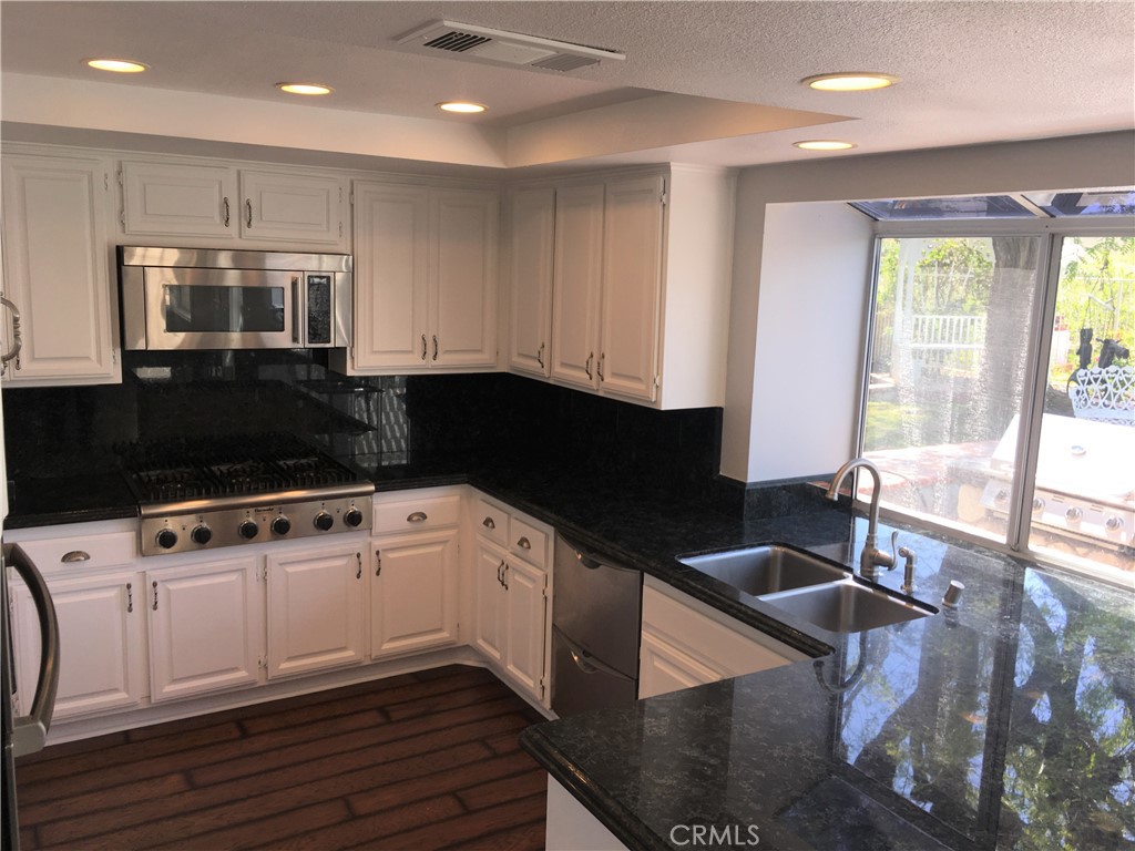 29022 Modjeska Peak Lane Lake Forest, CA 92679 - Photo 5 of 36 a kitchen with stainless steel appliances kitchen island granite countertop a stove a sink and a microwave