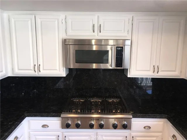 a kitchen with white cabinets and black appliances