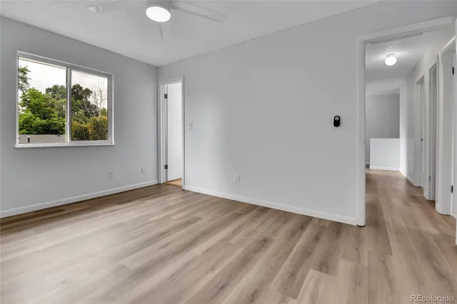 a view of an empty room with wooden floor and a window