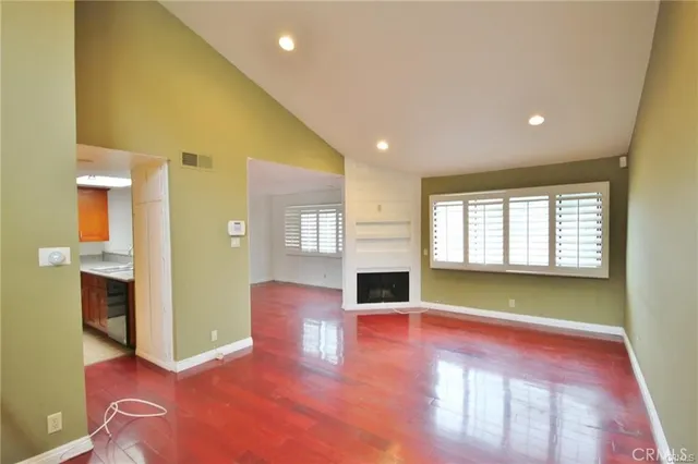 a view of an empty room with window and wooden floor
