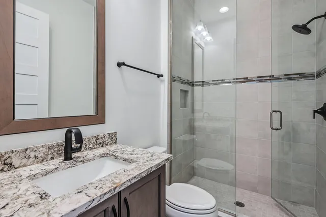 a bathroom with a granite countertop sink a toilet and shower