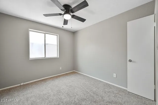 an empty room with a window and a fan