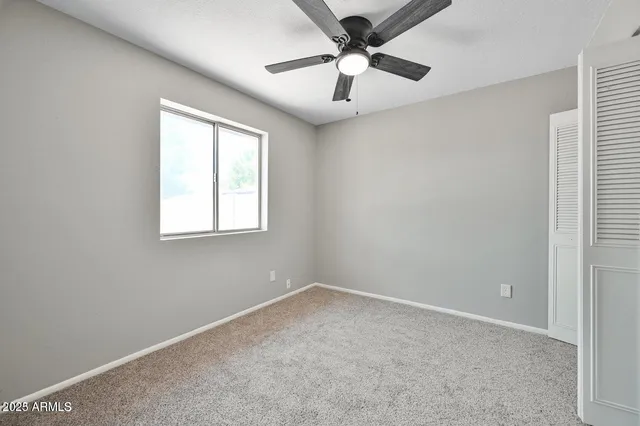 an empty room with a window and a fan