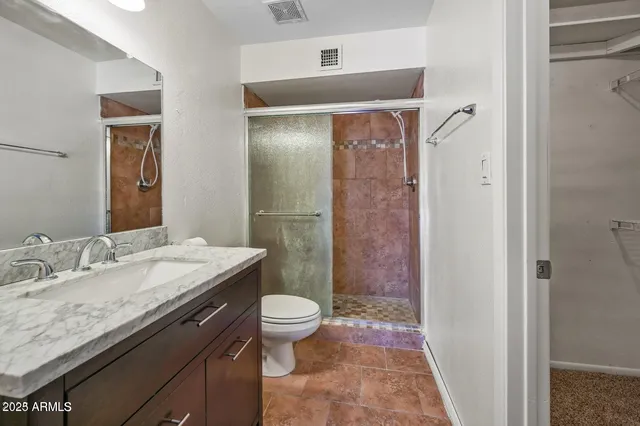a bathroom with a granite countertop sink a toilet a mirror and shower