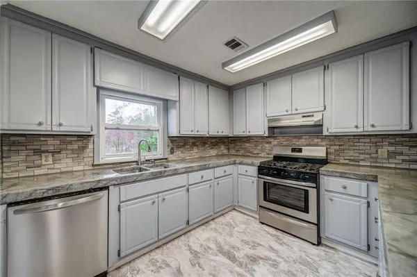 a kitchen with stainless steel appliances granite countertop a sink stove and cabinets