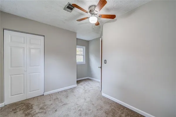 an empty room with closet and fan