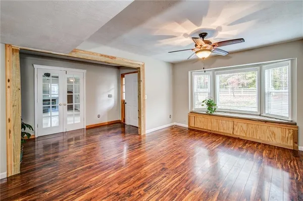 a view of an empty room with wooden floor and a window